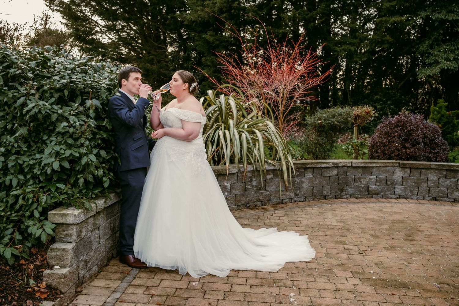 Romantic sunset wedding portrait on stone patio with autumn foliage in background.