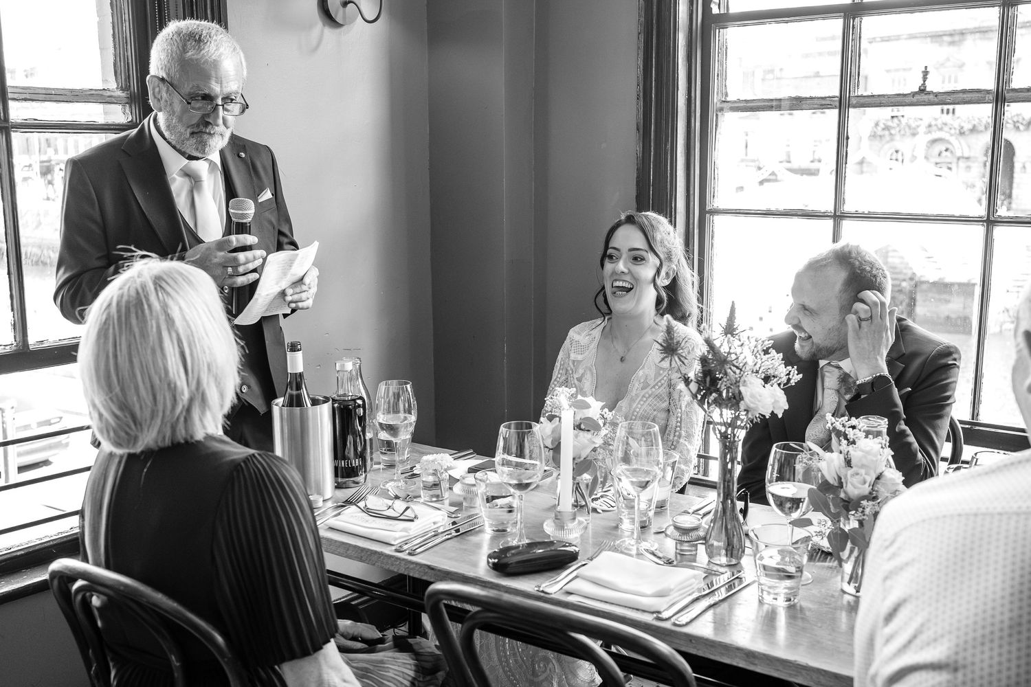 A busy lunchtime dining scene in a modern restaurant with natural light streaming through large windows.