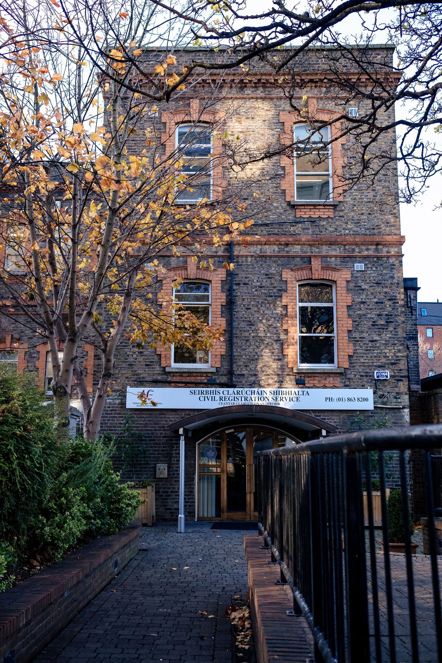Historic brick Civil Registration Service office building with autumn trees in Dublin, Ireland.