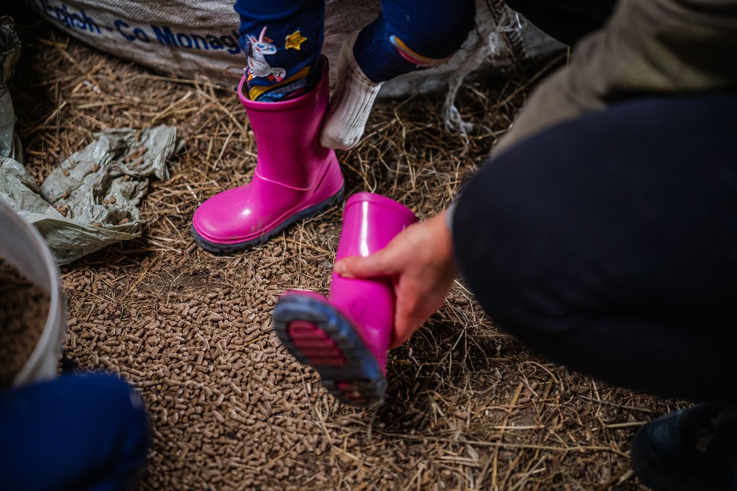 Pink boots visible among scattered wood chips on a playground surface.