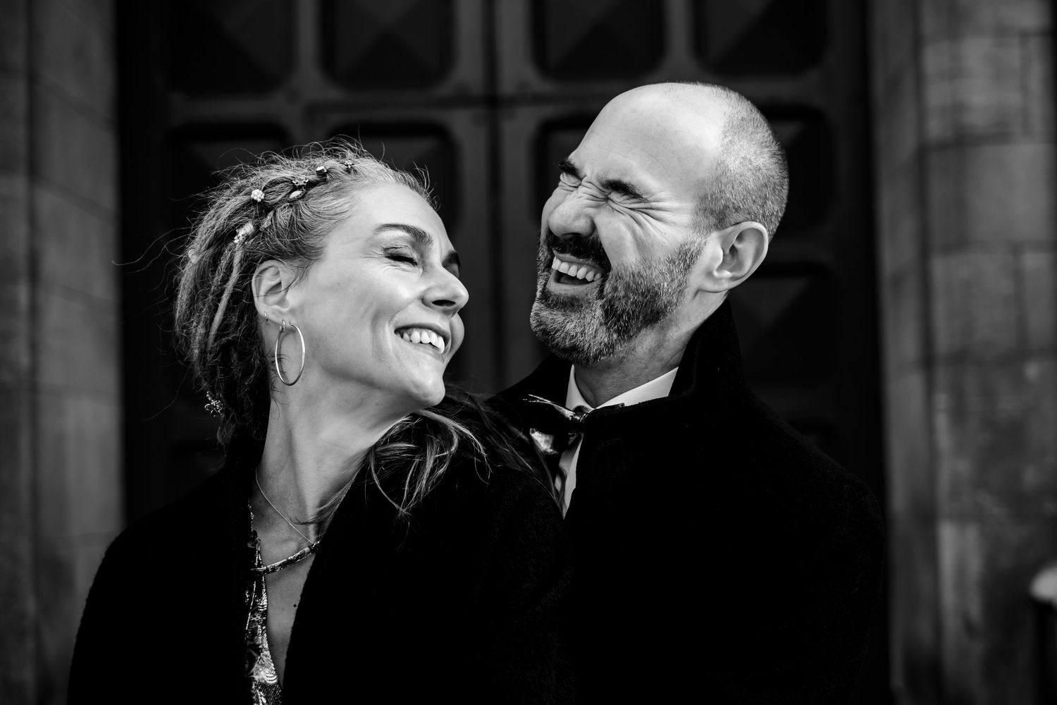 Black and white portrait of a joyful couple sharing a candid laughing moment.