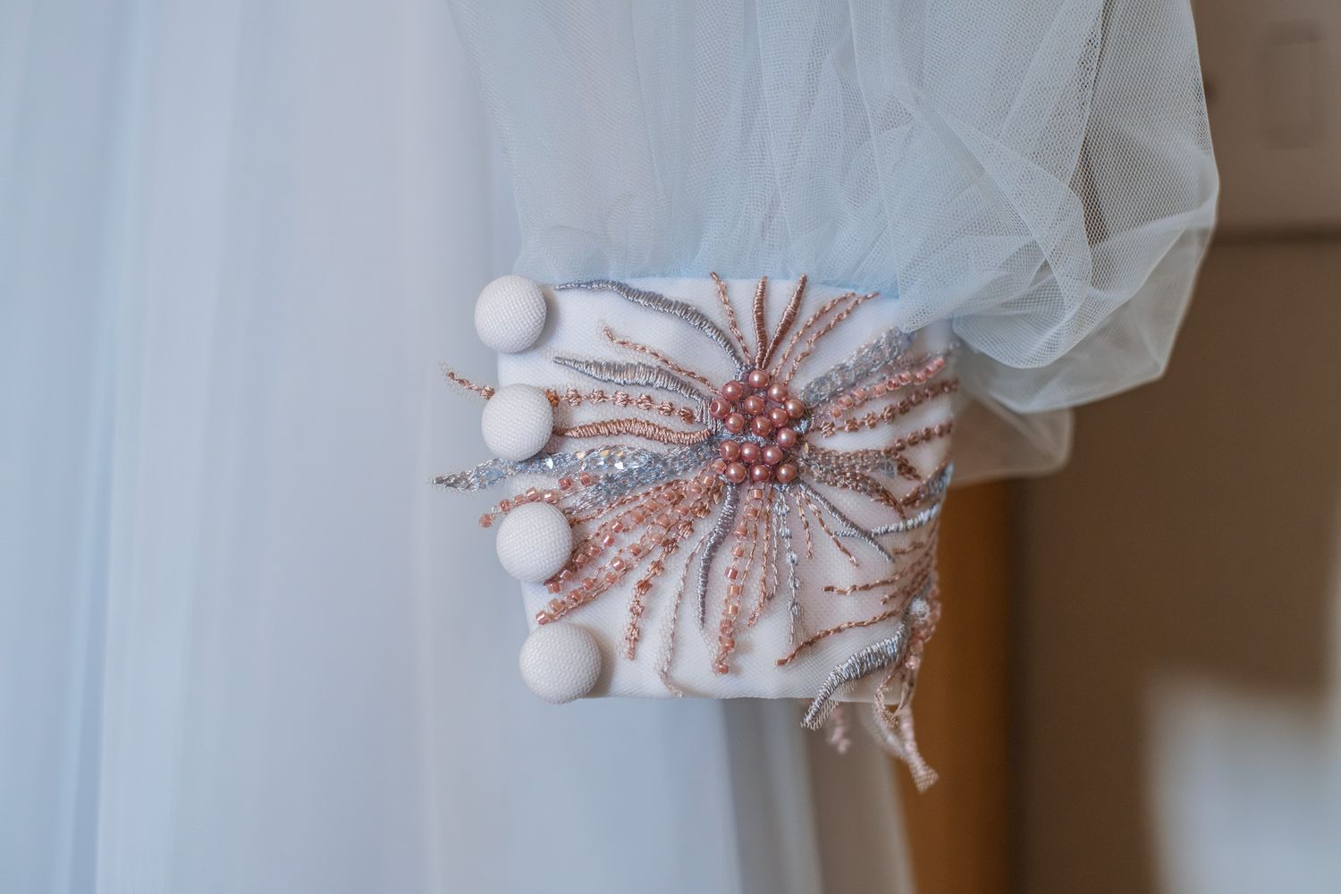 Elegant bridal clutch purse with rose gold beaded floral embroidery and pearl details against white tulle fabric.