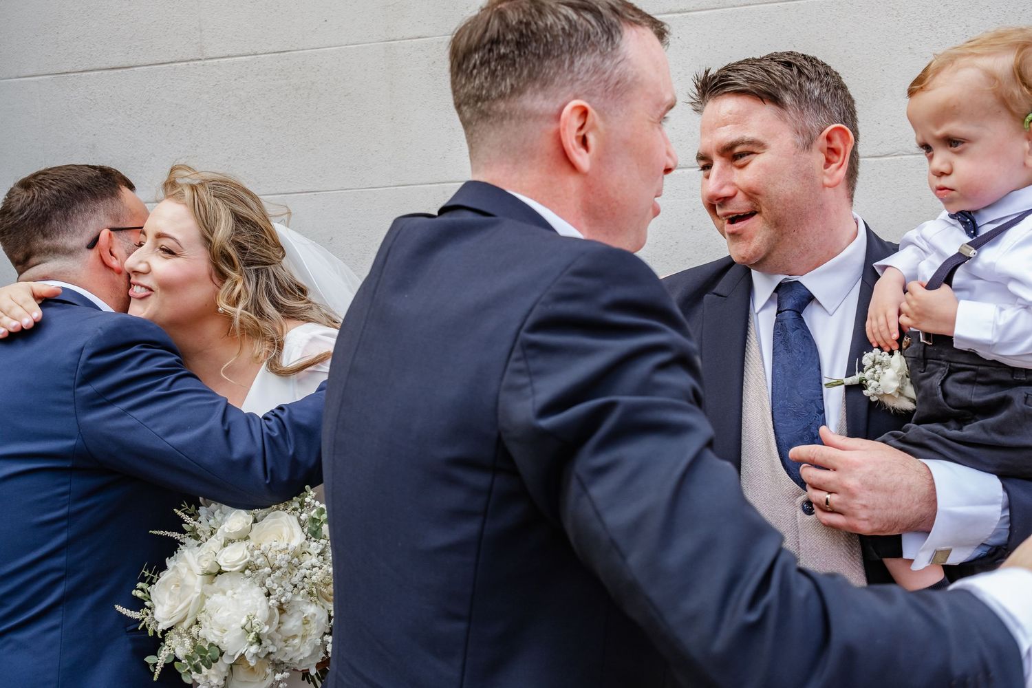Wedding party members share emotional embraces and celebrations outside.