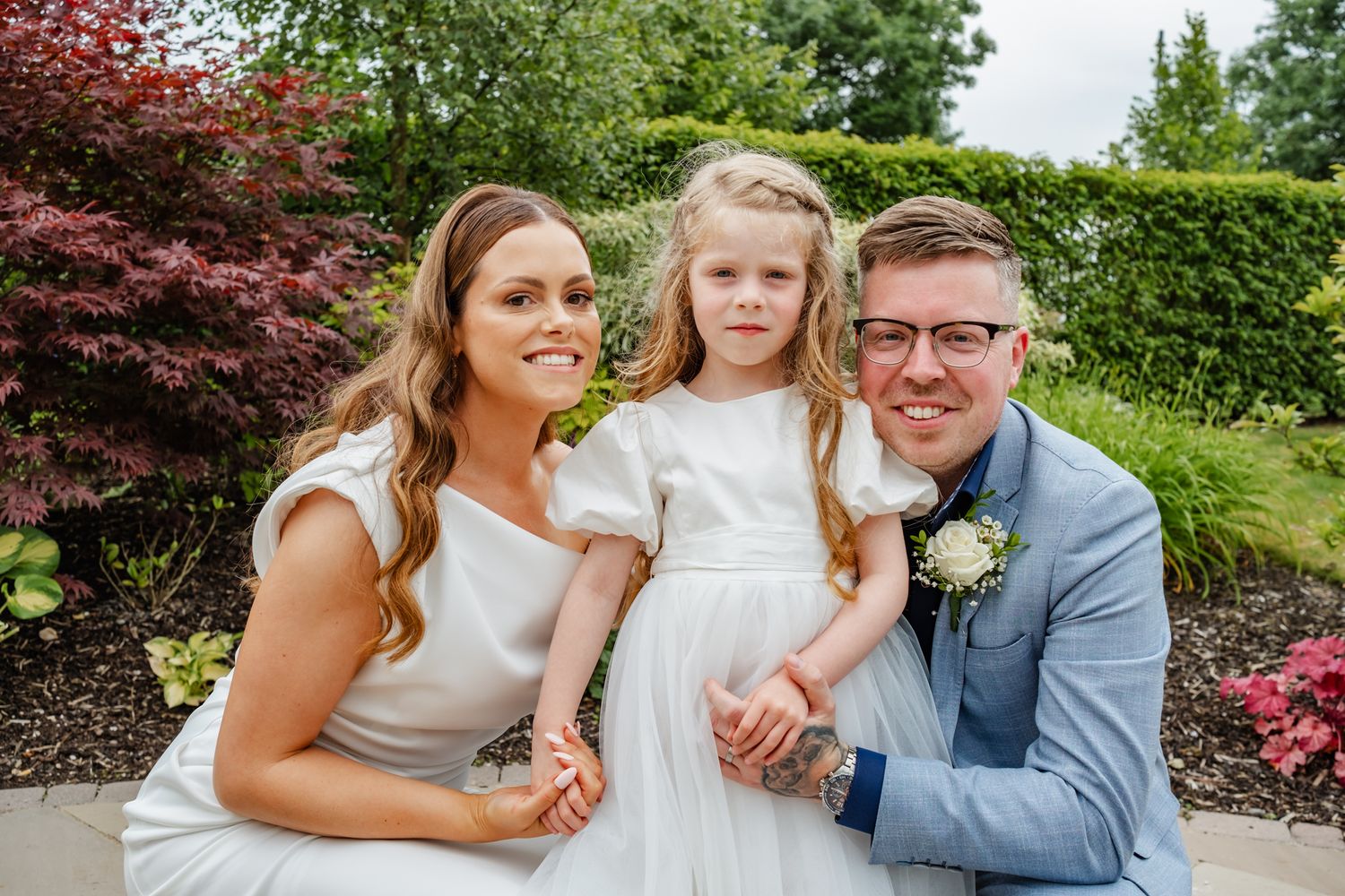 A wedding portrait in a lush garden setting with colorful flowers and greenery.