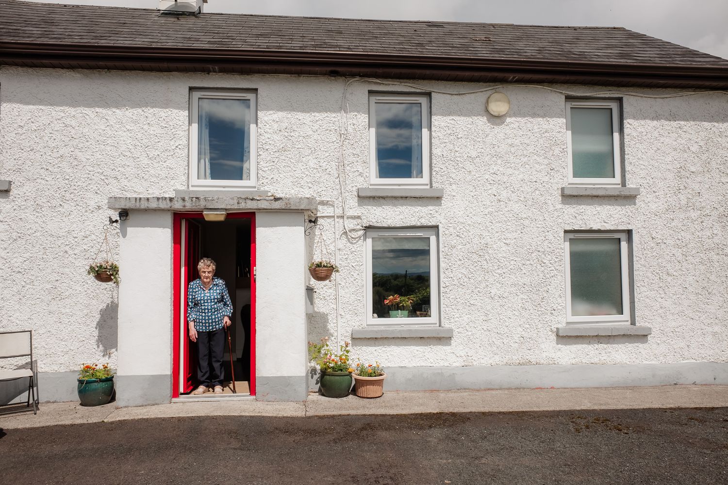 White cottage house with red door and window planters.