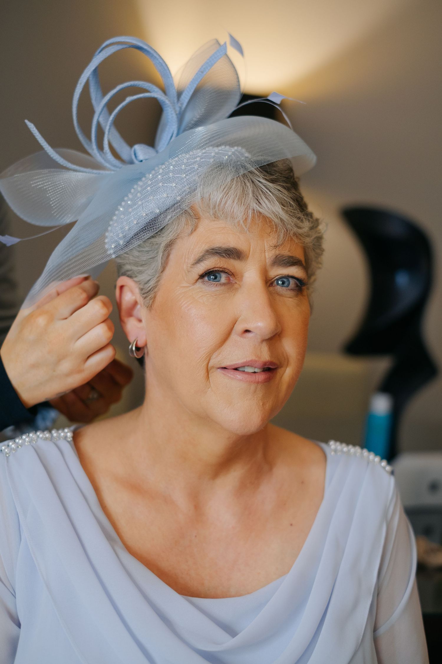 A series of five close-up shots showing someone wearing a delicate light blue fascinator and special occasion attire.