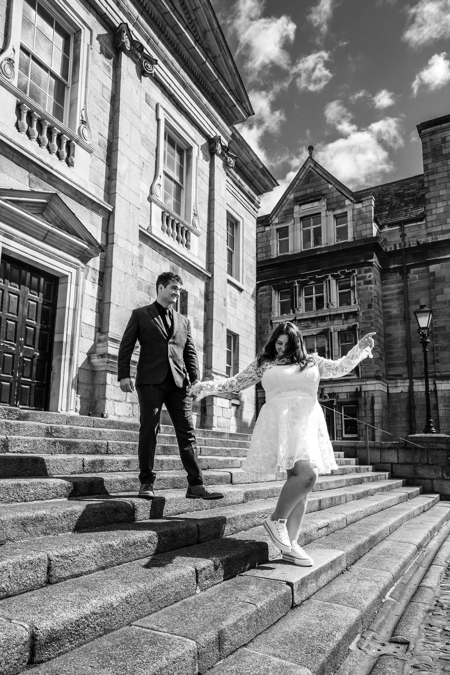 A couple on stone steps of a grand historic building with classical architecture.