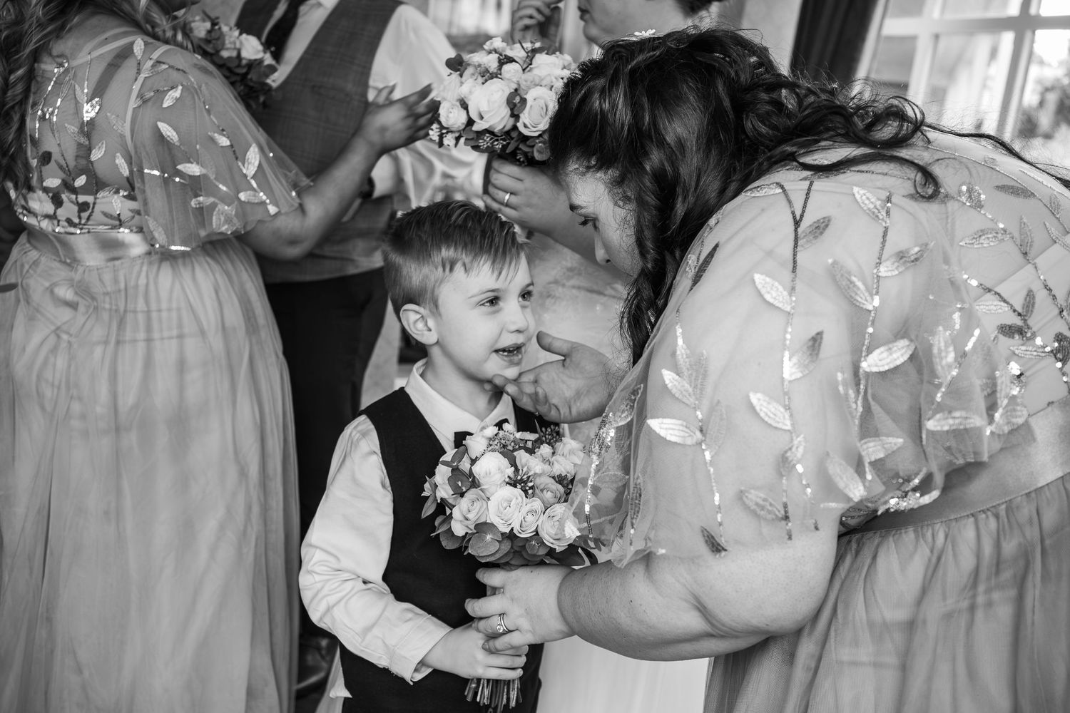 A touching black and white moment of wedding party members sharing a sweet interaction with flowers.