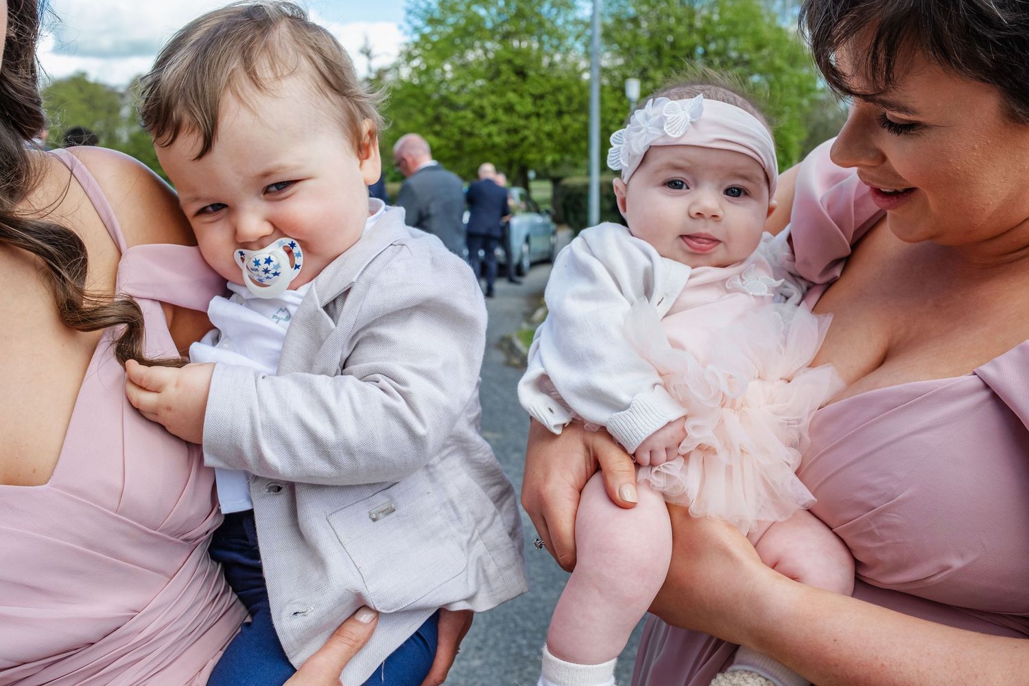 Sweet family moments captured with babies in pink and white outfits at outdoor gathering.
