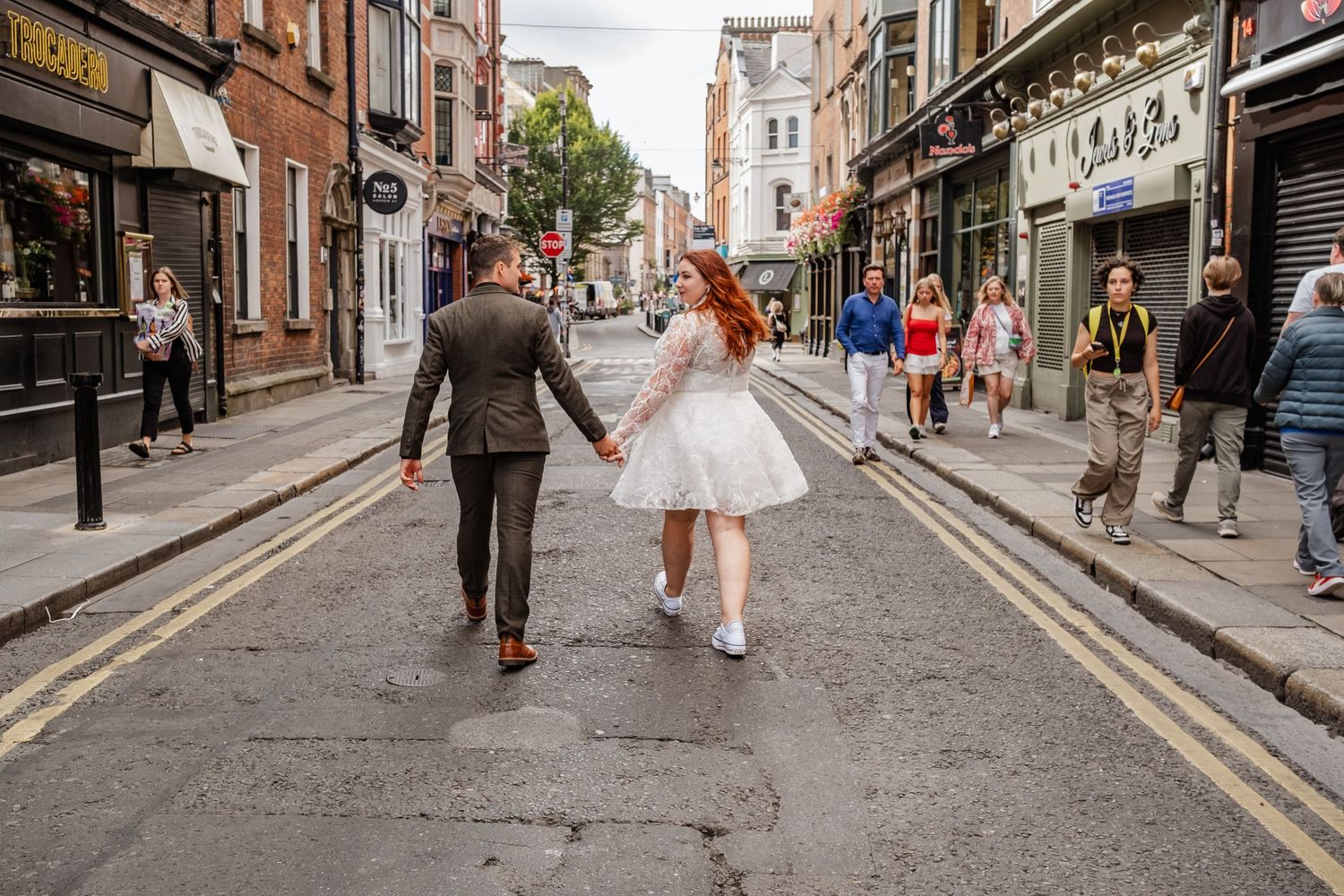 A couple walking hand in hand down a quaint Dublin city street.