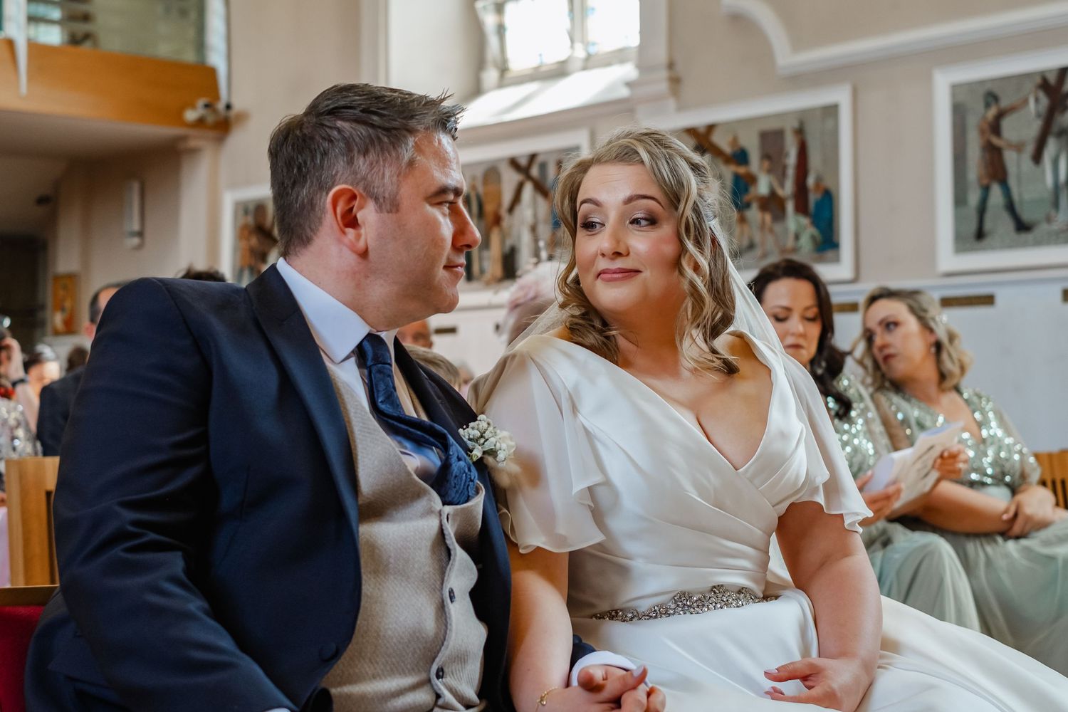 A couple shares an intimate moment in their wedding attire inside a beautifully decorated church.