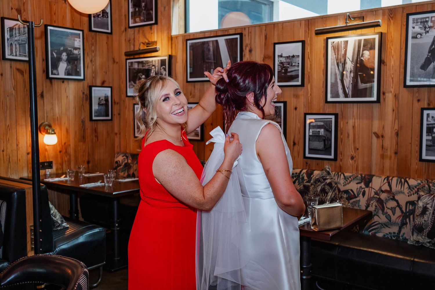 Wedding party gathering in rustic venue with wood paneling and framed photographs.