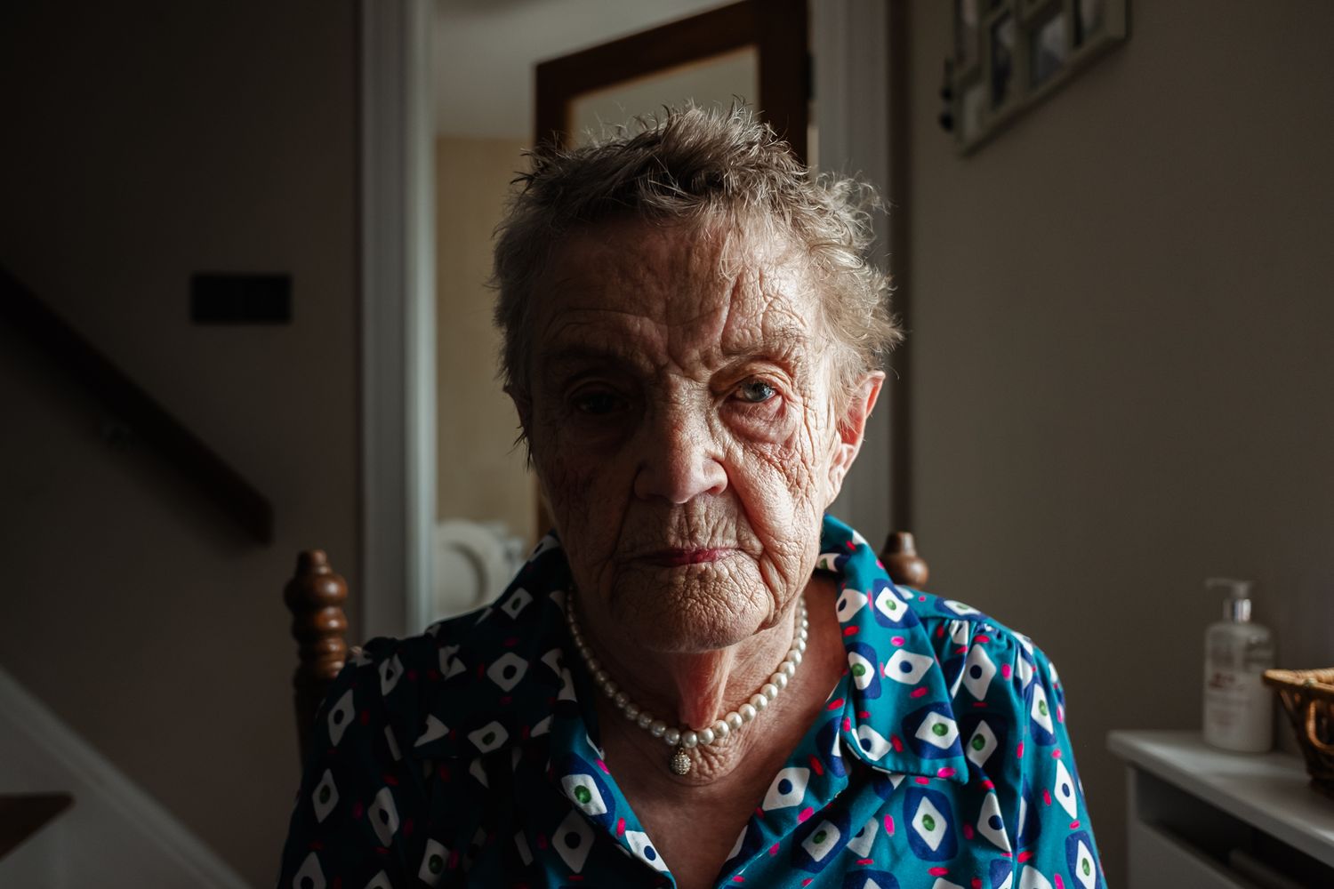 Close up portrait in dark lighting showing detailed facial features and blue patterned clothing.
