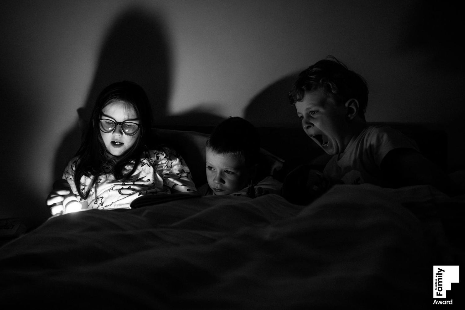A series of dark silhouettes illuminated by phone screens in a dimly lit environment.