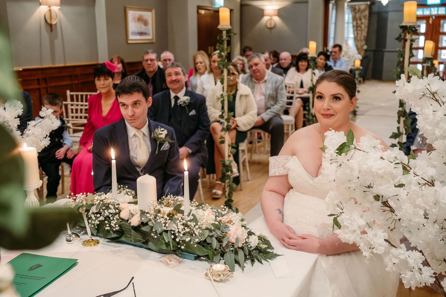 Wedding reception table decorated with lush greenery garlands and white floral arrangements.