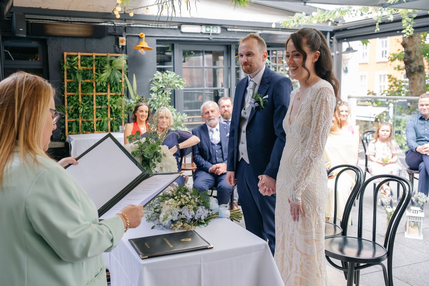 A modern wedding reception space with elegant table settings and greenery decorations.