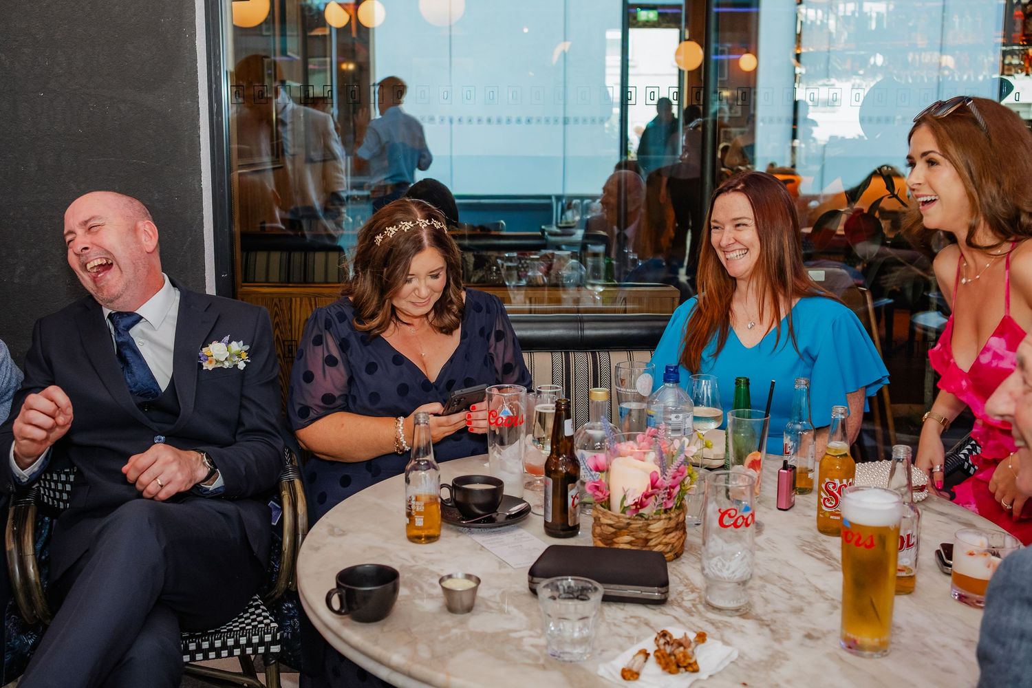 A lively social gathering of people enjoying drinks and conversation at a restaurant table.