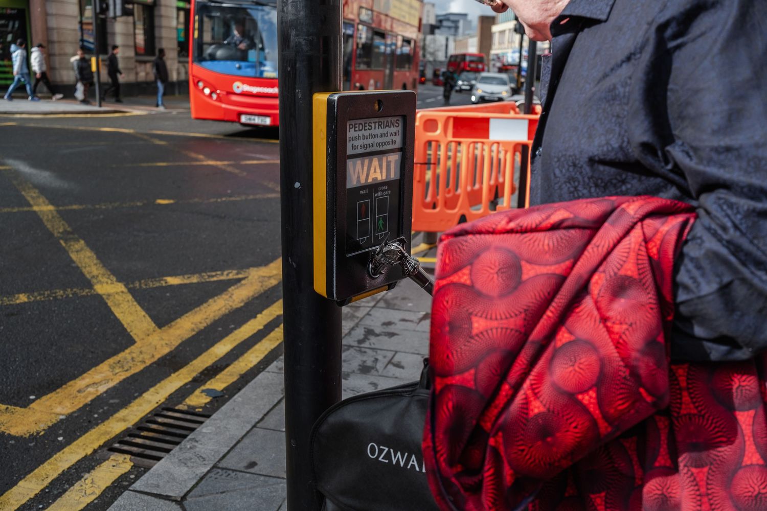 Red patterned bag against urban street background with construction barriers.