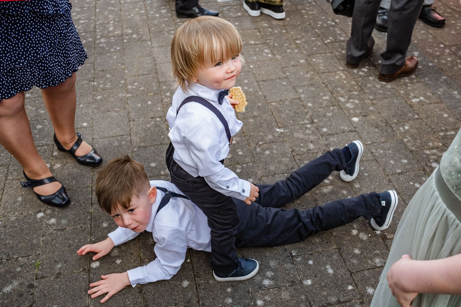 Children in matching formal attire play on the ground at a wedding celebration.