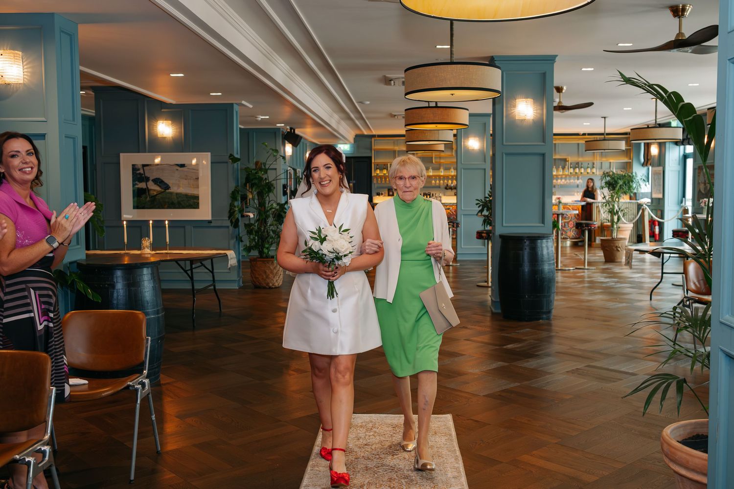 Wedding reception venue with teal columns and modern decor featuring guests mingling in an open space.