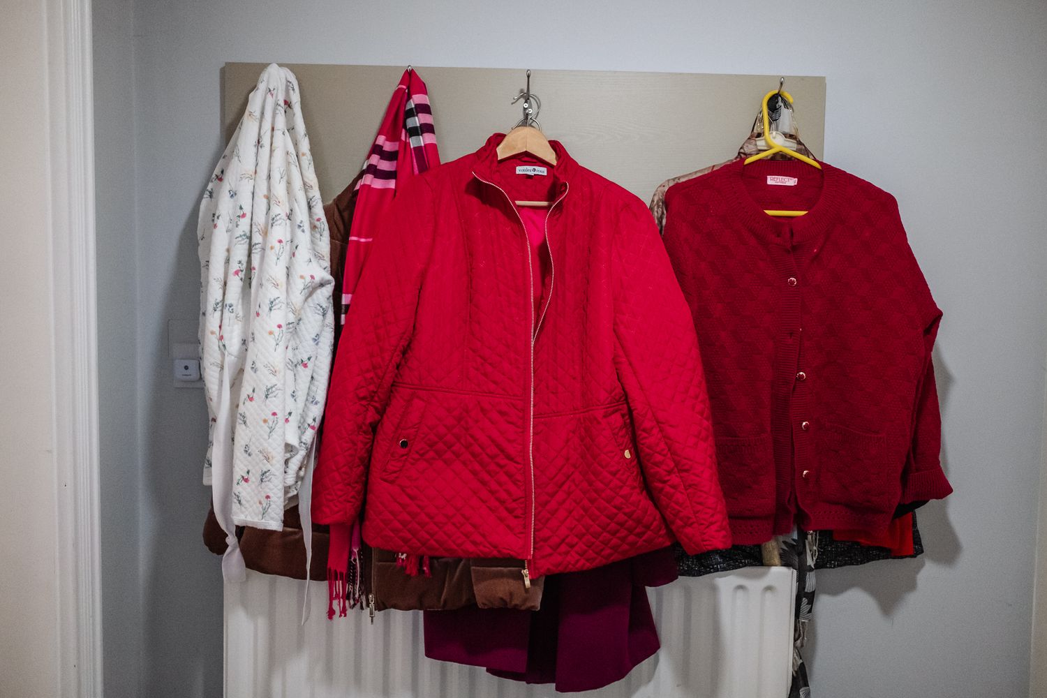 Red jackets and white garments hanging on coat hooks.