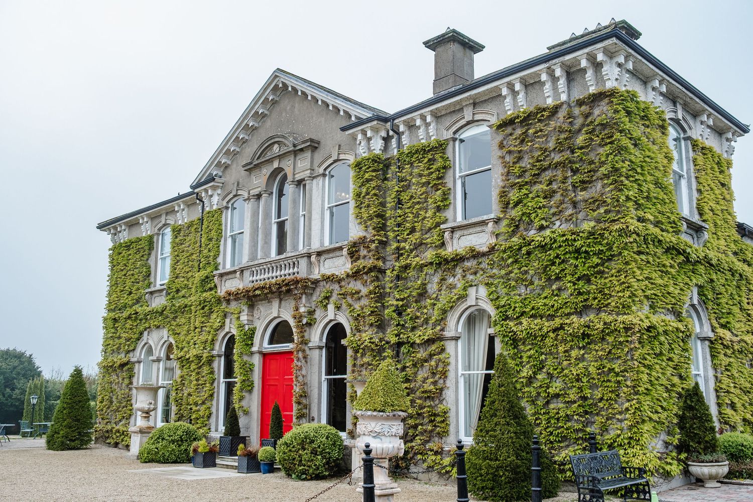 Exterior view of a grand historic mansion with ivy-covered walls and classic architecture in daylight.