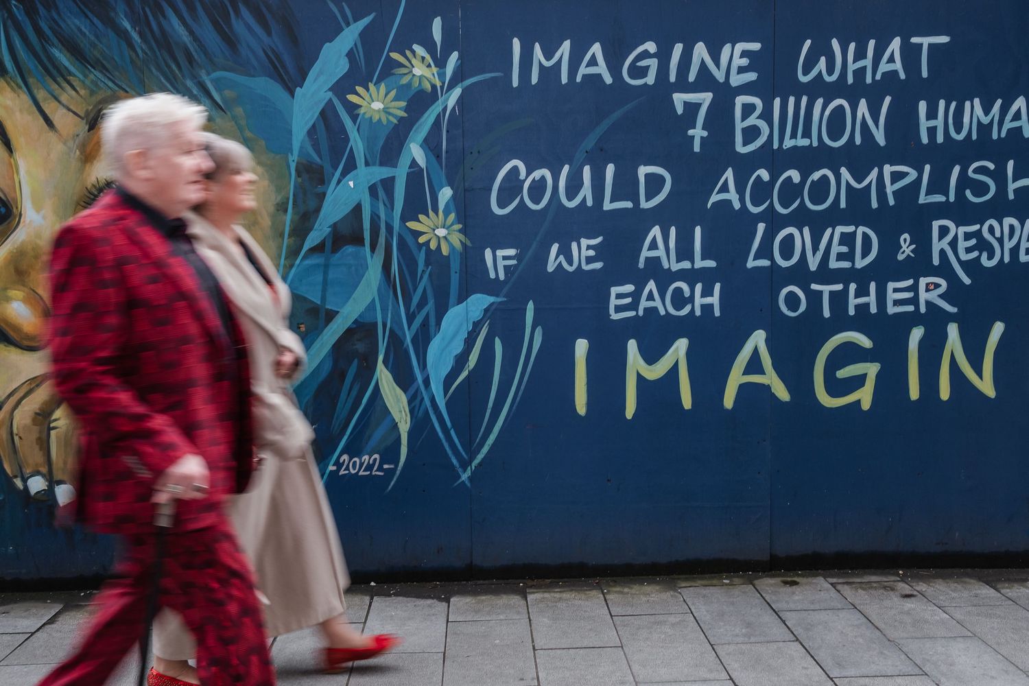 Inspirational mural about 7 billion humans with painted floral designs on blue wall.
