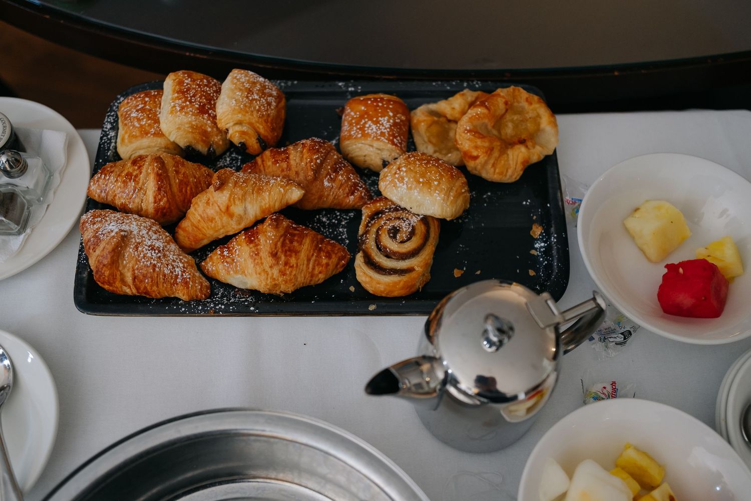 A buffet table displays an assortment of fresh pastries, croissants and breakfast items in a restaurant setting.