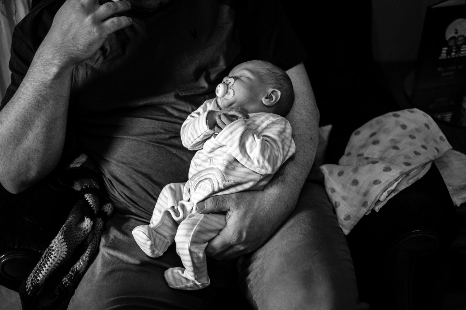 Black and white photo of a tiny infant resting peacefully on someone's lap.