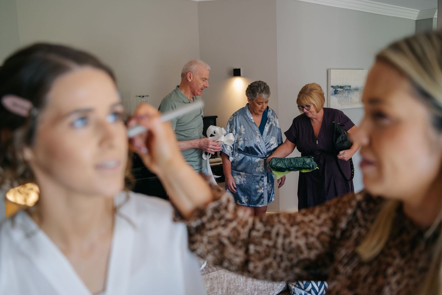 Candid moments of wedding preparations with people getting ready in a bright room.