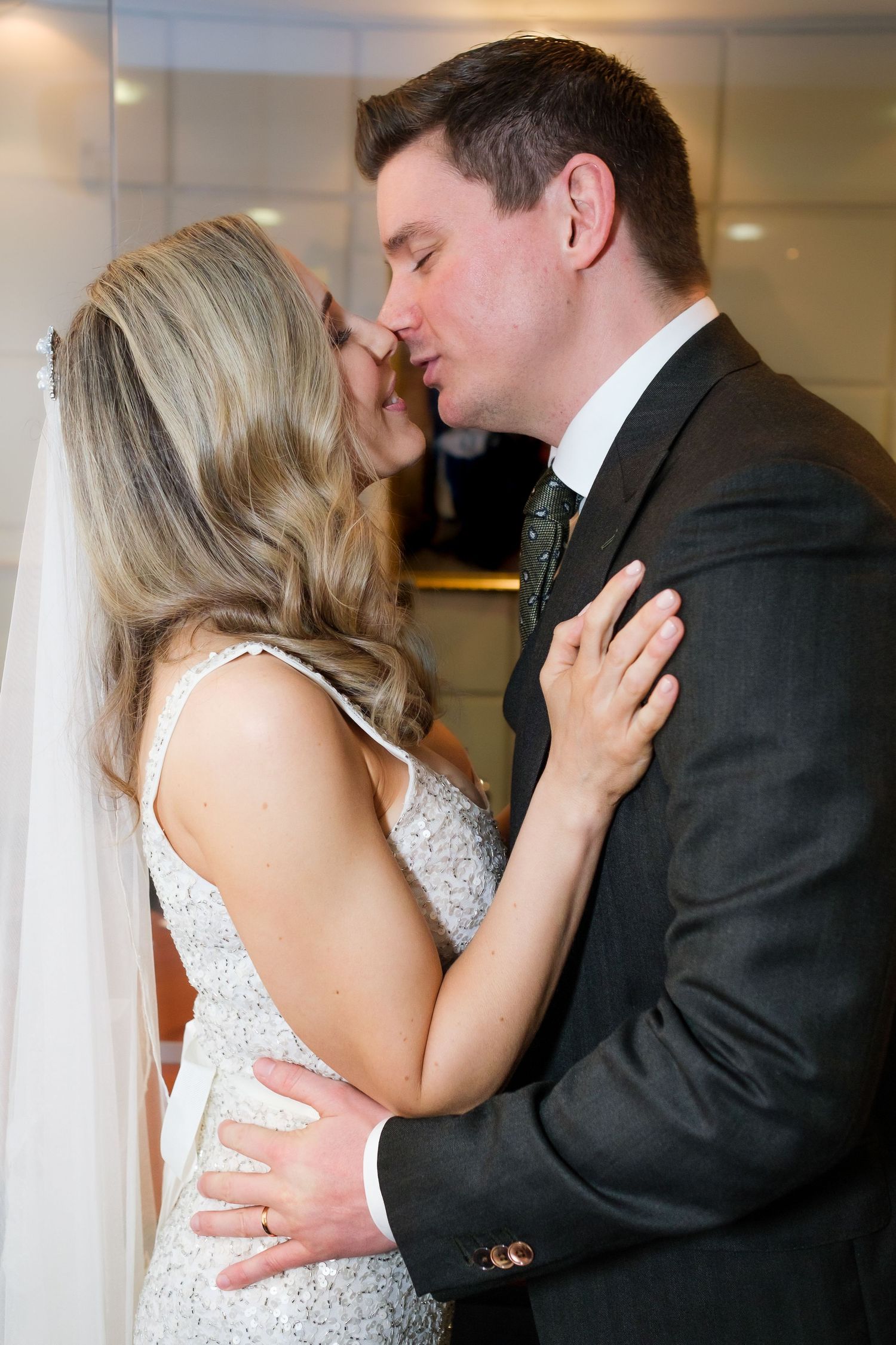 Romantic couple shares an intimate moment at their wedding, with the bride in a sparkly dress and groom in a dark suit.