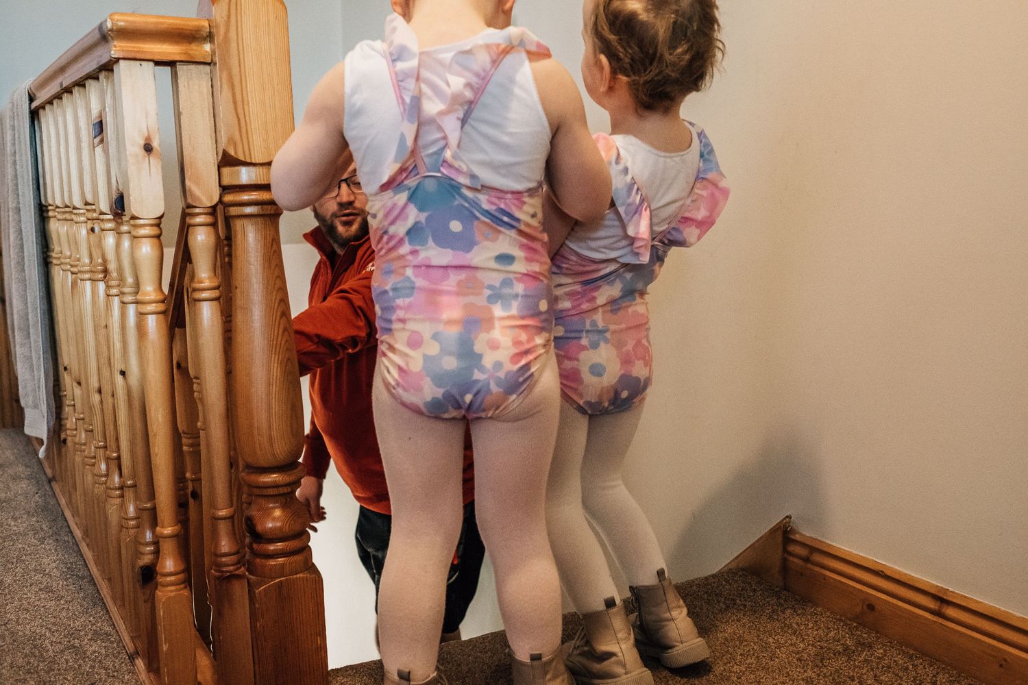 Two figures wearing matching floral outfits standing on carpeted stairs.