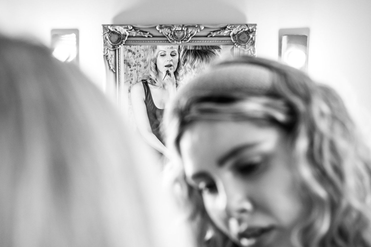 Black and white image showing mirror reflections during a makeup session.