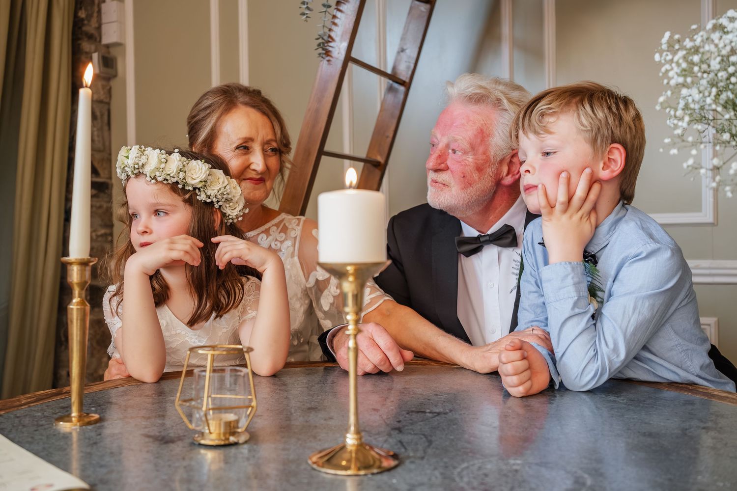 Two children and grandparents gather around candles at a wedding celebration, sharing a warm and joyful family moment.