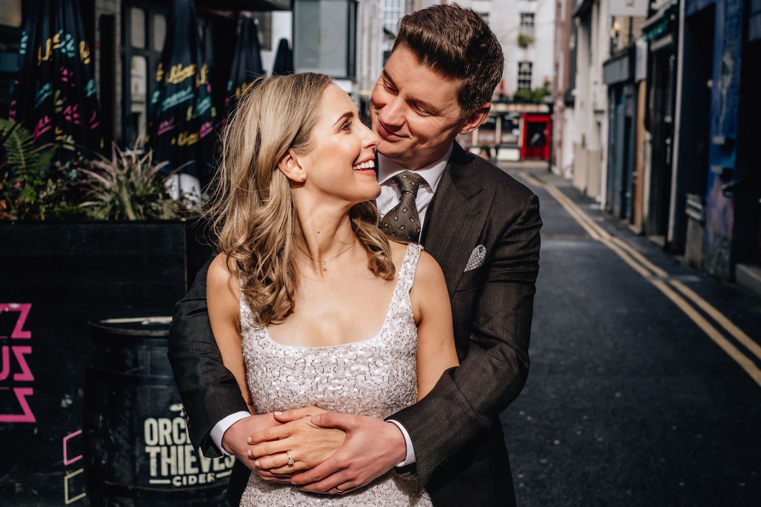 Couple laughs together during romantic photoshoot in urban setting.