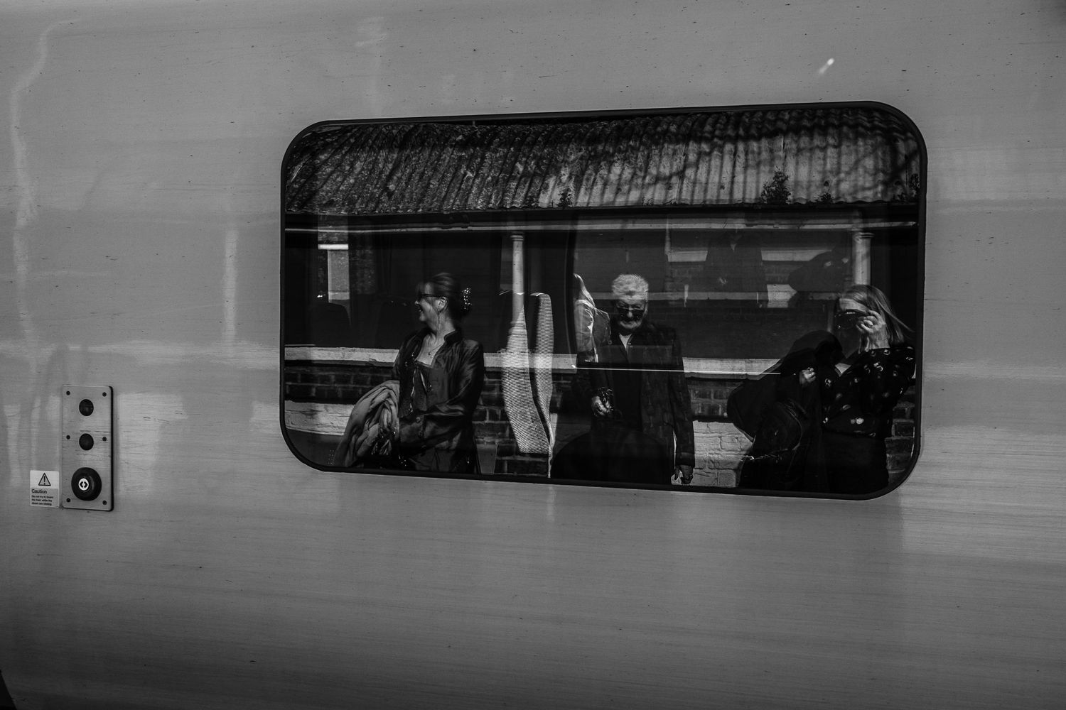 Black and white photograph showing silhouettes through a train or subway window.