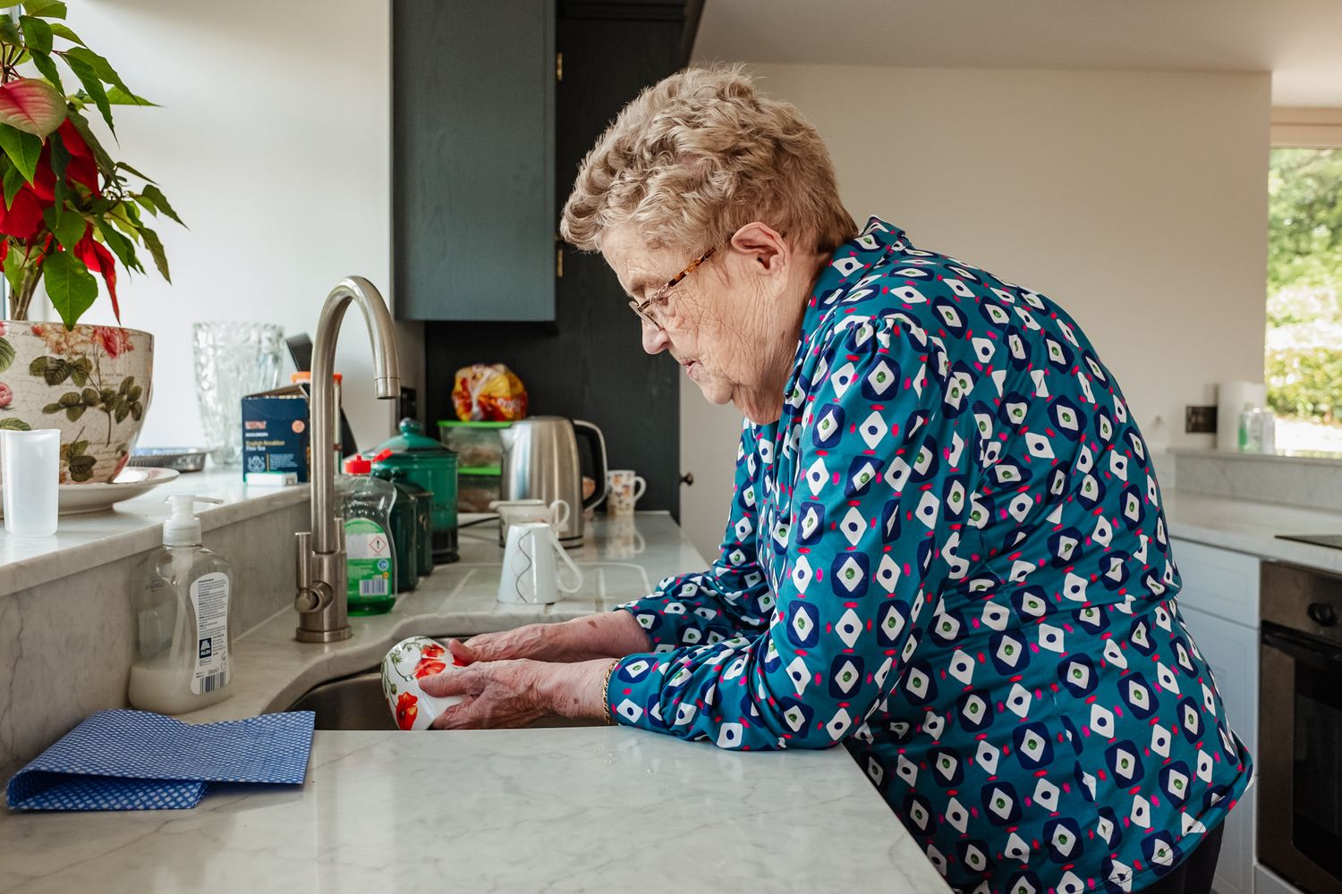 Person in blue patterned clothing preparing food at kitchen counter.