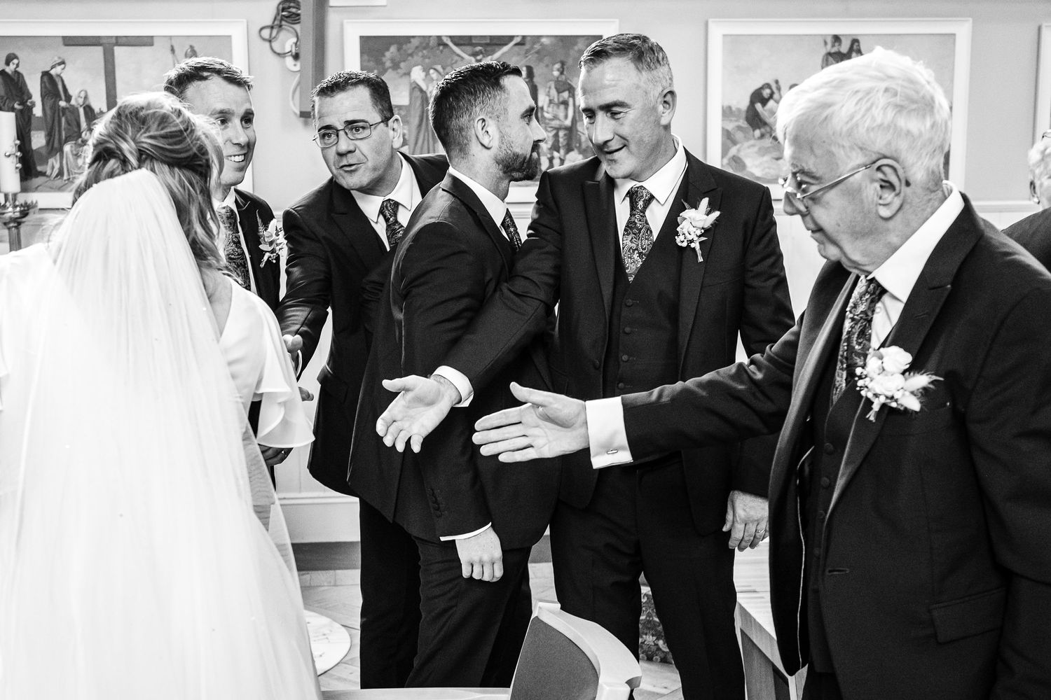 A black and white candid moment of wedding guests interacting during the celebration.