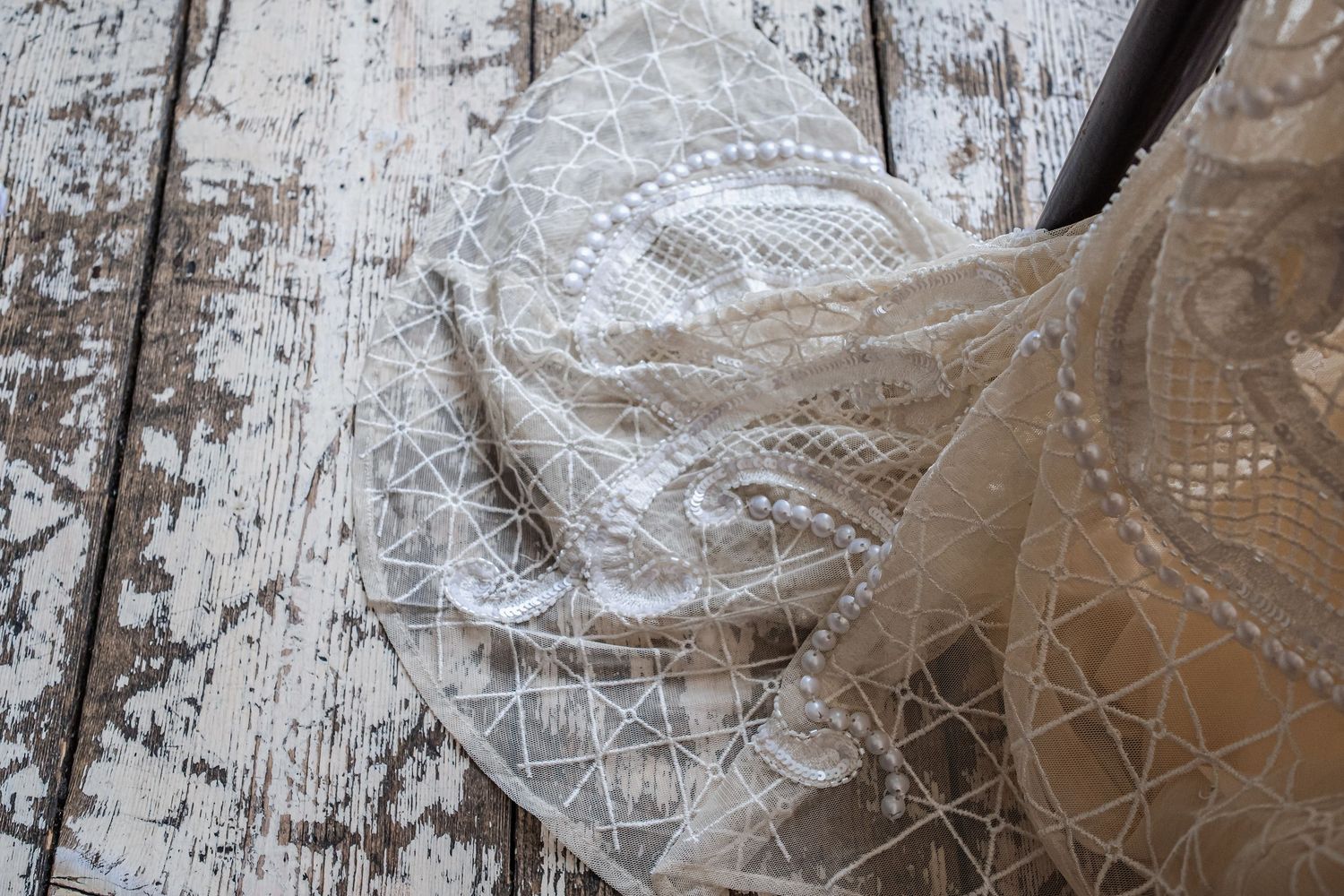 Delicate white lace fabric with intricate floral patterns shown in close-up detail.