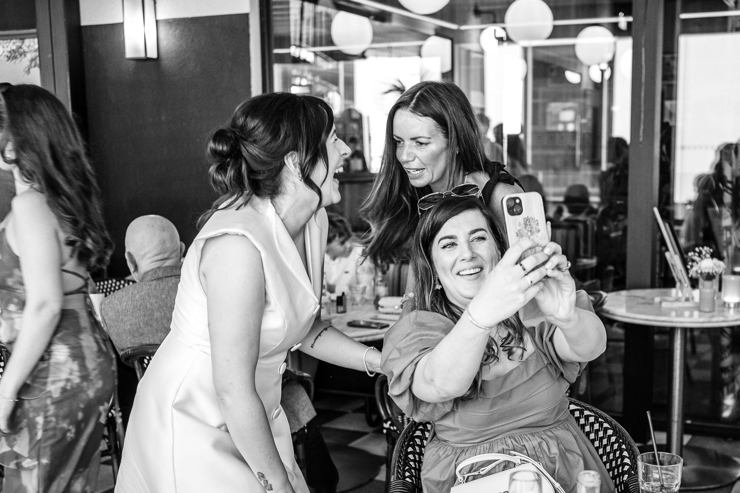 Candid black and white panoramic photo showing diners and staff inside a busy restaurant interior.
