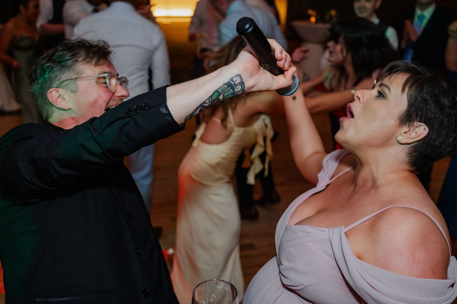 Wedding party guests enthusiastically dancing and celebrating during reception festivities.