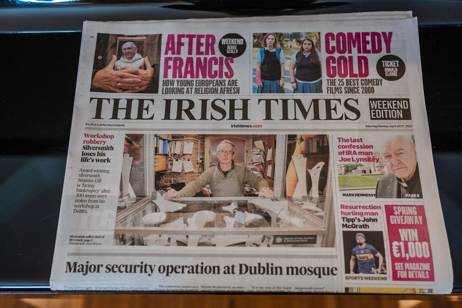 Collection of Irish newspapers including The Irish Times displayed on a dark surface.