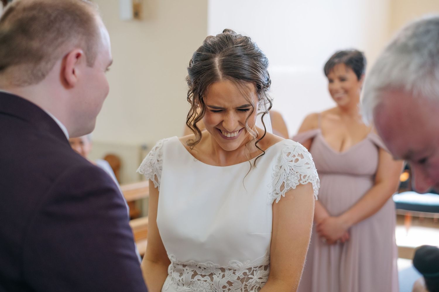 A bride smiles and shares an intimate moment with her father during wedding preparations.