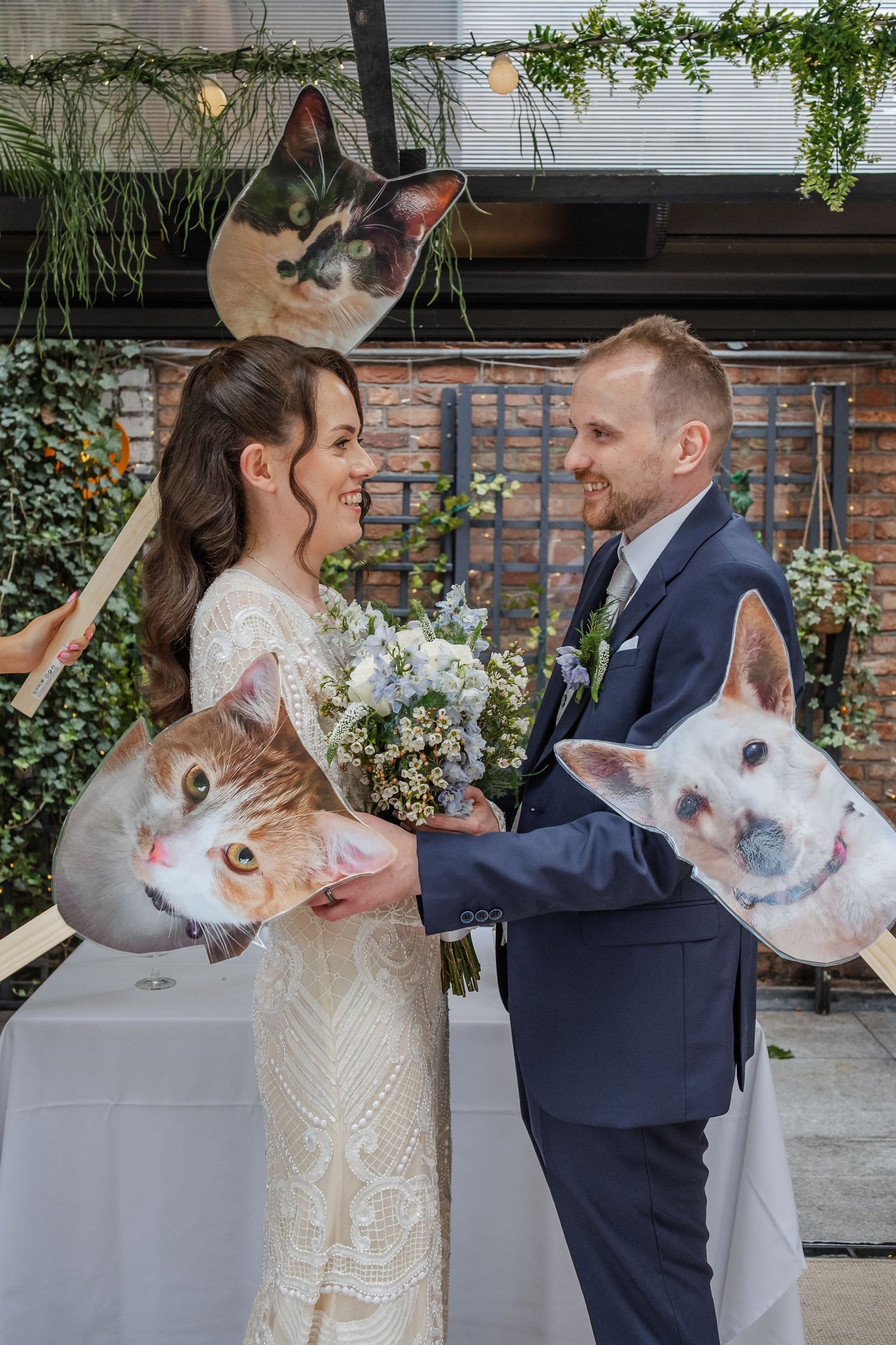 Wedding couple posing with fun pet-themed photo props against a garden backdrop.