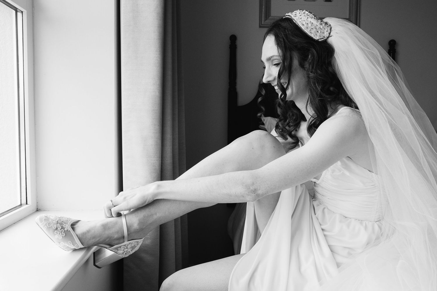 Black and white photos show a bride getting ready in front of windows.