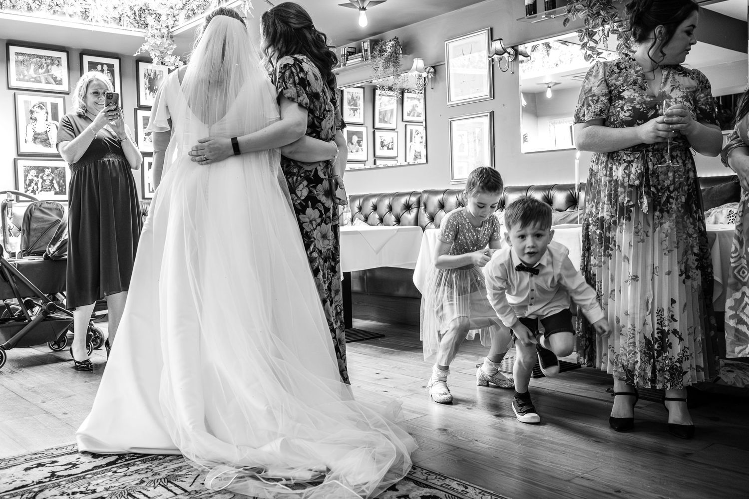Black and white photo of wedding celebration in restaurant with dancing guests.