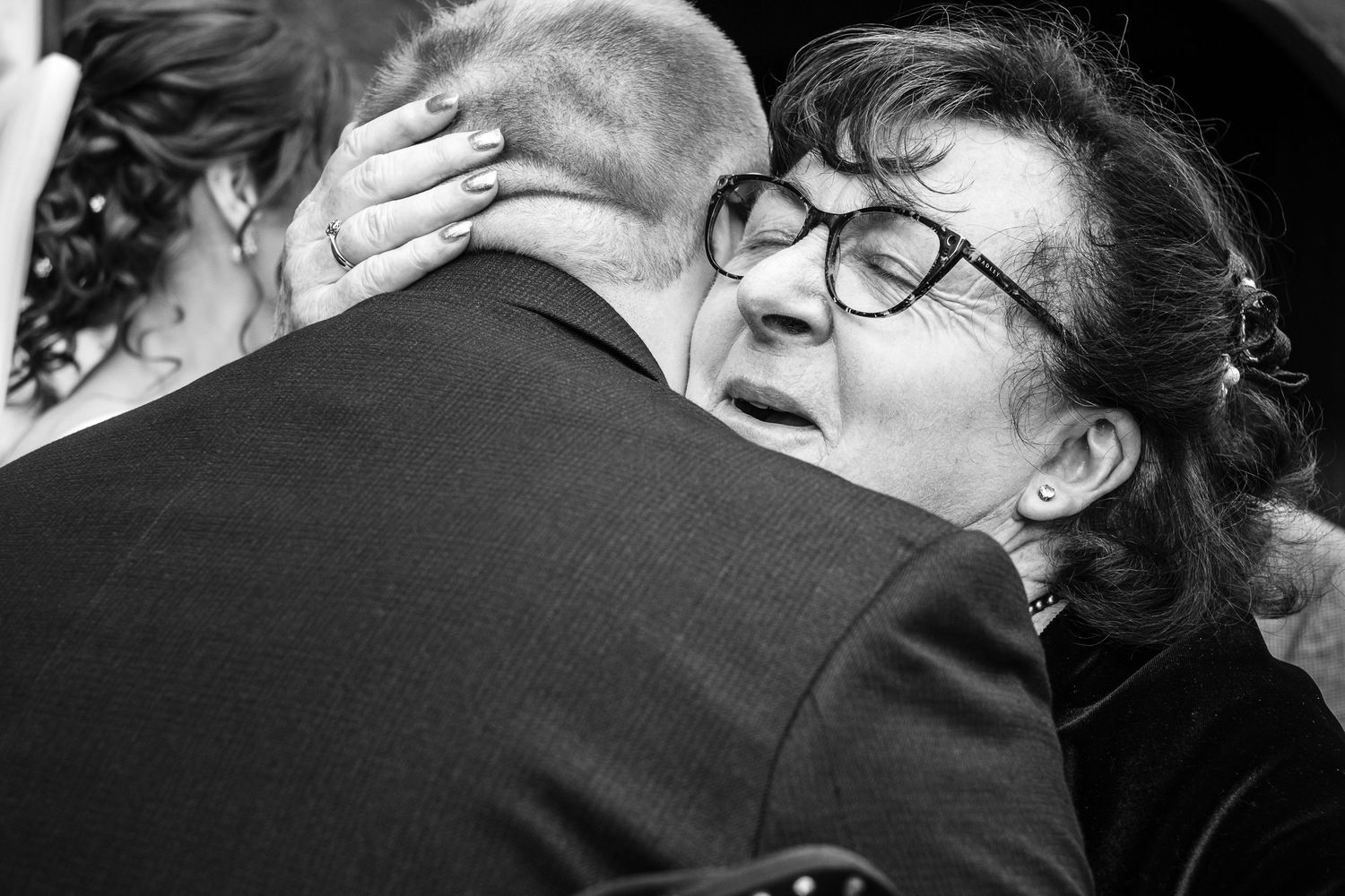 Wedding guests sharing an emotional moment at an outdoor ceremony, embracing and smiling together.