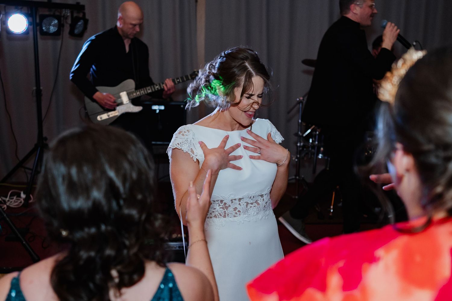 Dance party guests celebrate on a dark dance floor with disco lights illuminating the festive atmosphere.