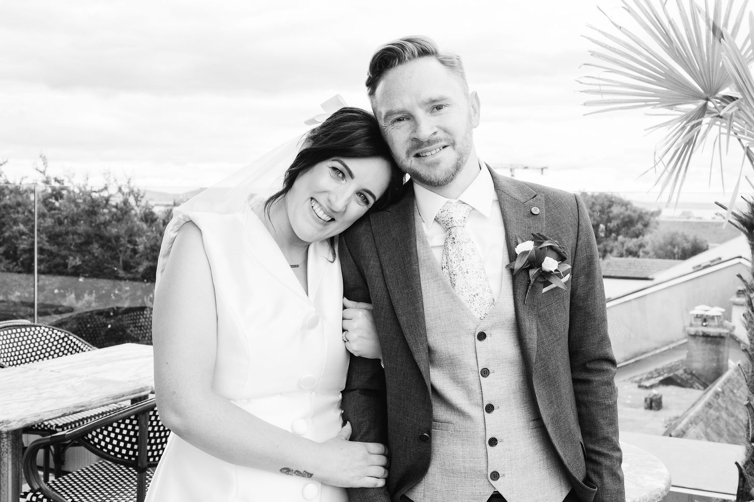 Wedding portrait session outdoors with natural lighting and palm fronds in background.