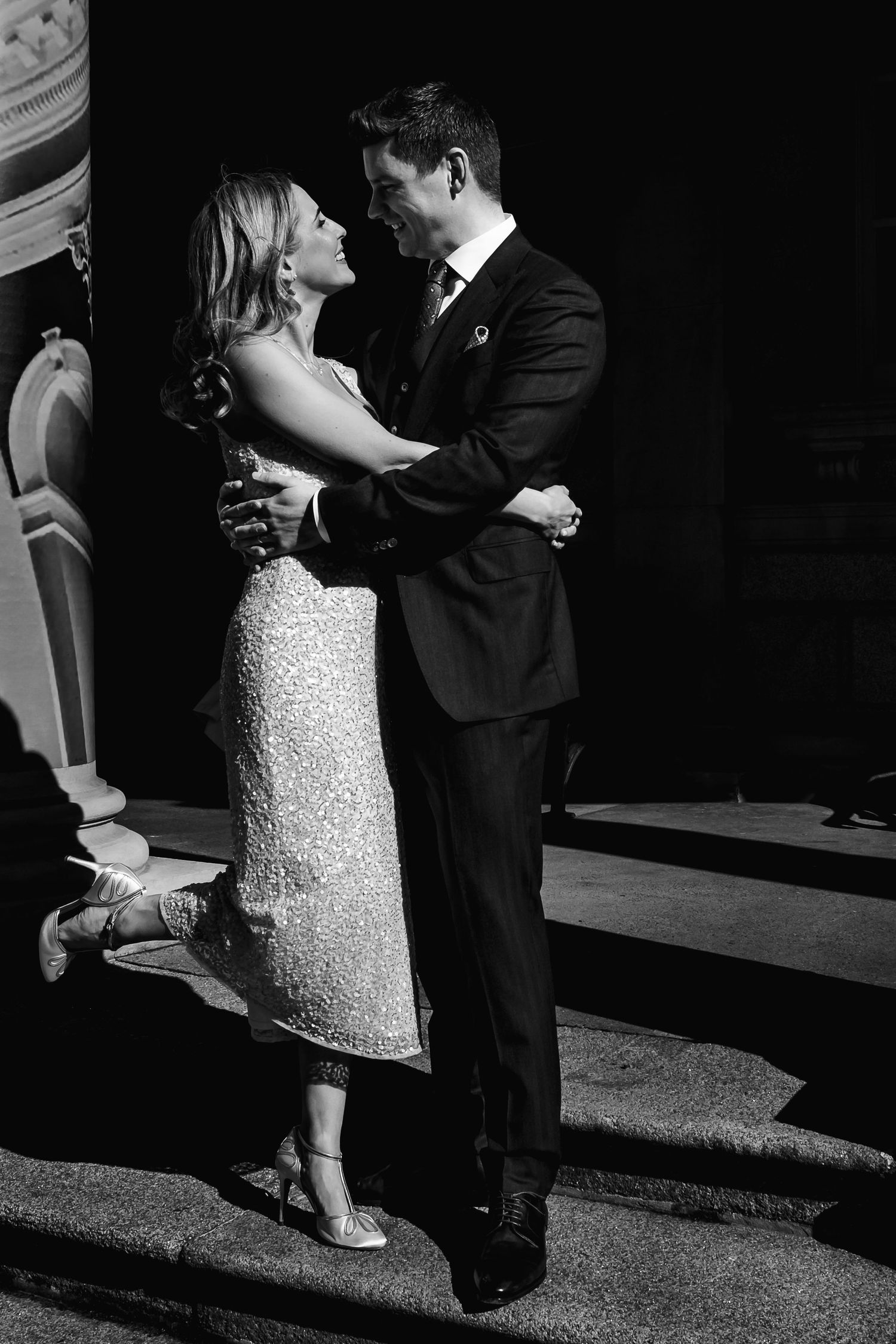 Dramatic black and white portrait of couple in formal wear sharing intimate dance pose.